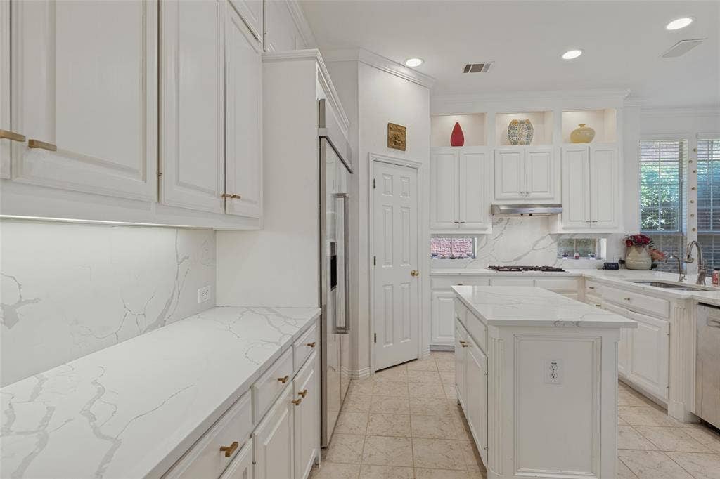 Kitchen featuring white cabinetry, stone-surface countertops with continuous backsplashes, a central island, recessed lighting, and stainless-steel appliances