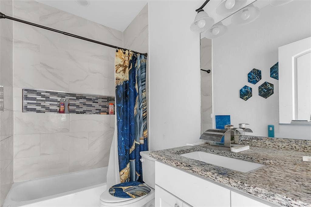 2002 Clay Street, Mabank, TX 75147 Bathroom with granite-look vanity, tub and shower combo and tile surround with mosaic niche