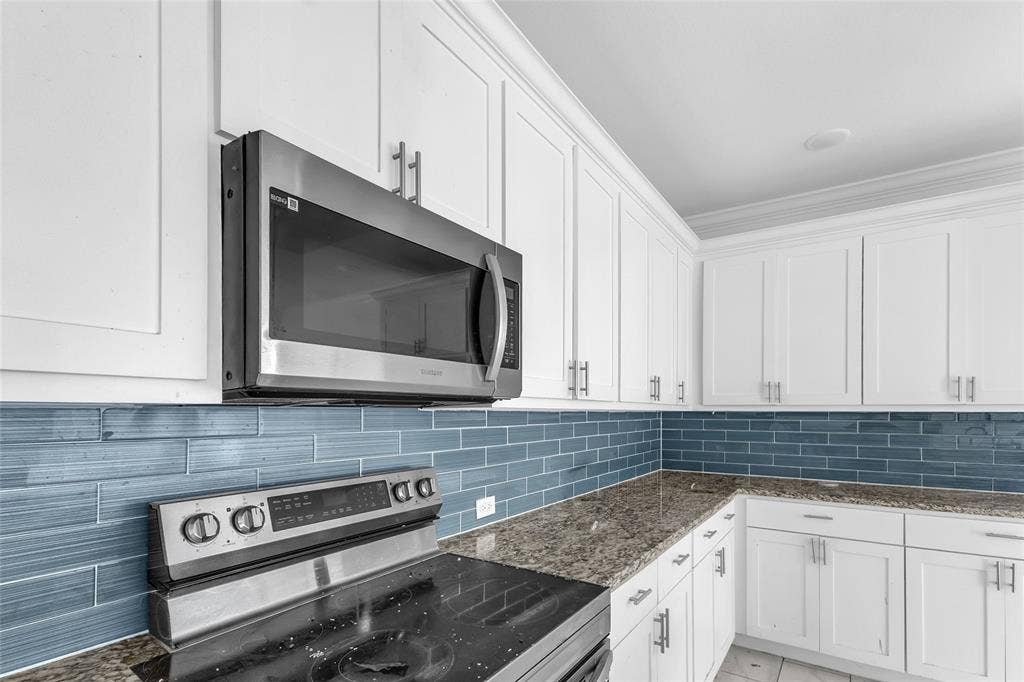 2002 Clay Street, Mabank, TX 75147 Stainless range and microwave with blue glass tile backsplash and white shaker cabinets