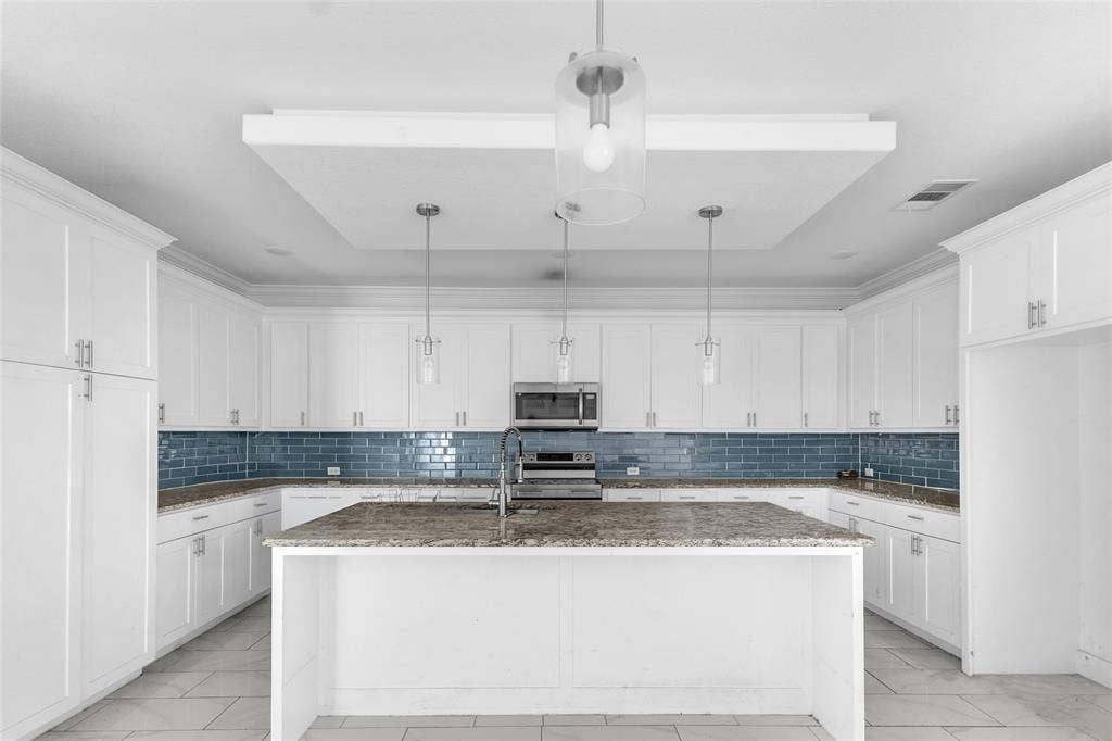 2002 Clay Street, Mabank, TX 75147 Kitchen with center island, tall white cabinetry, pendant lights and tray ceiling detail