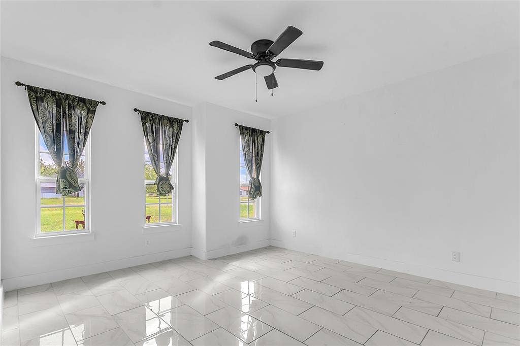 2002 Clay Street, Mabank, TX 75147 Front room with three tall windows, ceiling fan and large-format tile flooring