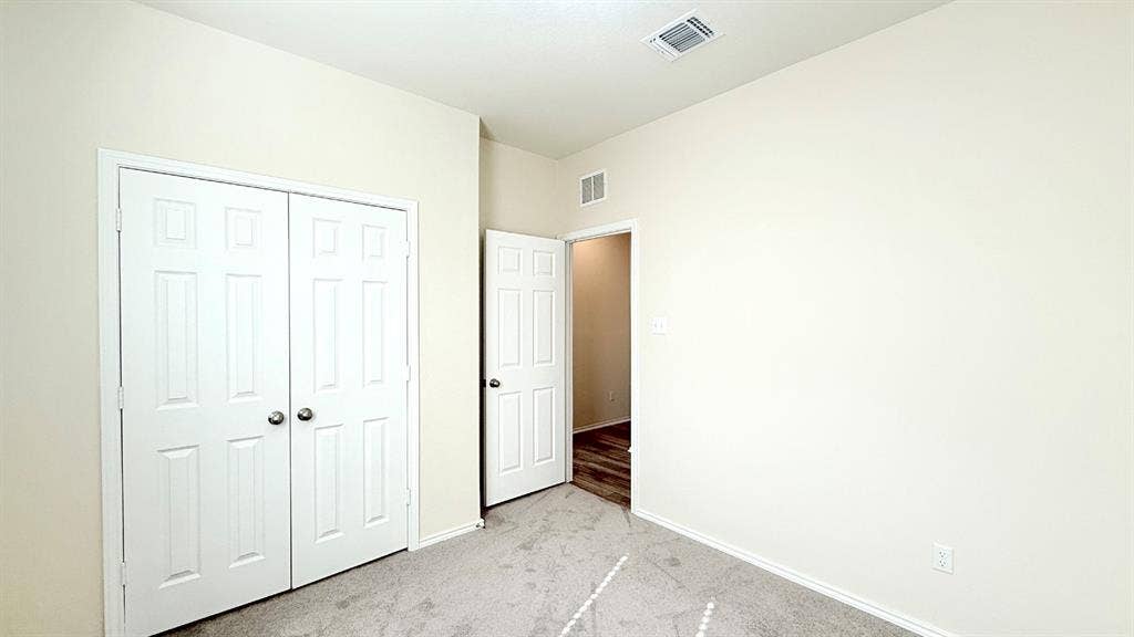 113 Onna Street, Taylor, TX 76574 Neutral-toned interior space featuring light-colored wall paint, plush carpeting, white six-panel closet doors, and an open interior door