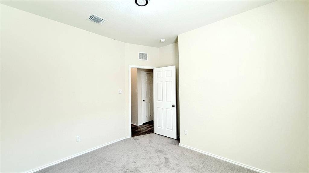 113 Onna Street, Taylor, TX 76574 Neutral-toned interior space featuring light-colored wall paint, plush carpeting, and a six-panel door