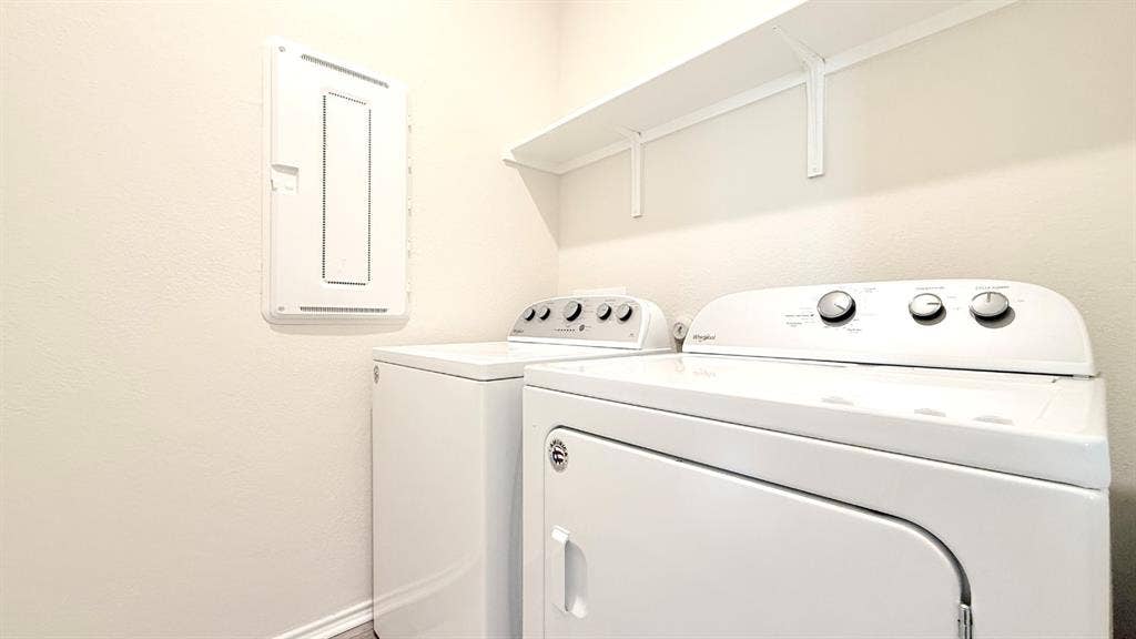 113 Onna Street, Taylor, TX 76574 Utility area featuring white top-load laundry appliances, wall-mounted electrical panel, and elevated storage shelving