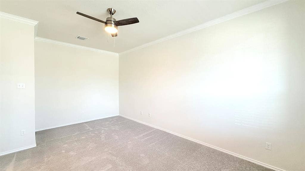 113 Onna Street, Taylor, TX 76574 Neutral interior room featuring crown molding, neutral carpeting, and a ceiling-mounted light fixture with a fan