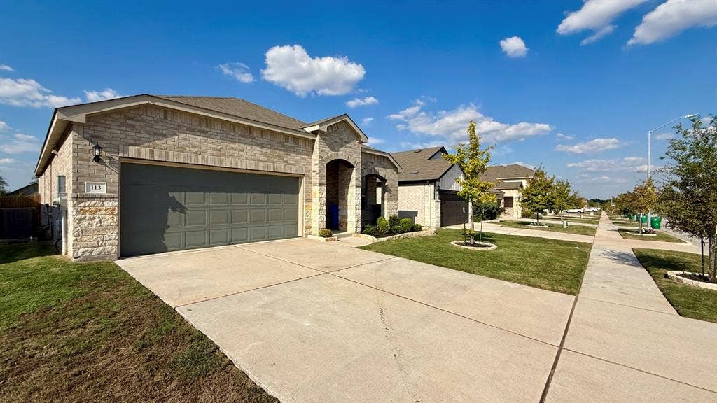 113 Onna Street, Taylor, TX 76574 Single-story exterior featuring masonry stone veneer, an attached two-car garage, and concrete driveway