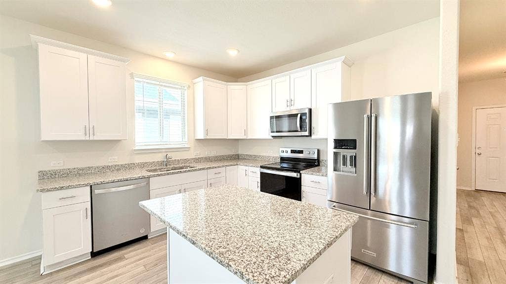 113 Onna Street, Taylor, TX 76574 Kitchen featuring white shaker-style cabinetry, stone-finish countertops, stainless steel appliances, a center island, and wood-finish flooring