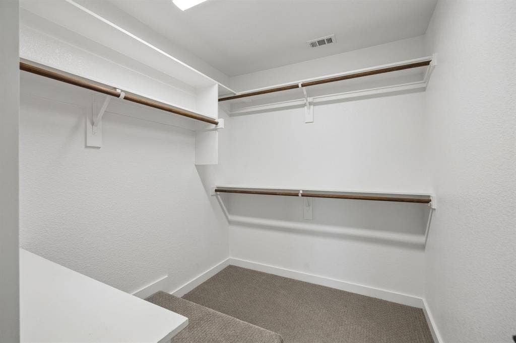 1901 N Carroll Avenue, #104, Dallas, TX 75204 Walk-in closet featuring multi-level white shelving, integrated wooden clothing rods, and wall-to-wall carpeting