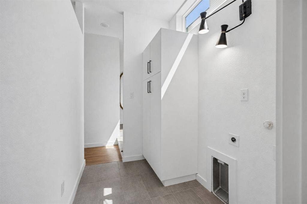 1901 N Carroll Avenue, #104, Dallas, TX 75204 Built-in white floor-to-ceiling cabinetry with matte black hardware, ceramic tile flooring, and wall-mounted dual-head lighting fixture