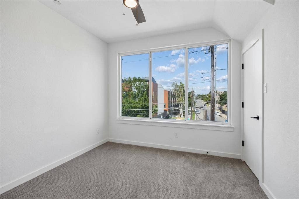 1901 N Carroll Avenue, #104, Dallas, TX 75204 Neutral interior room featuring large picture windows, gray carpeting, a ceiling fan, and a single swing door with matte black hardware