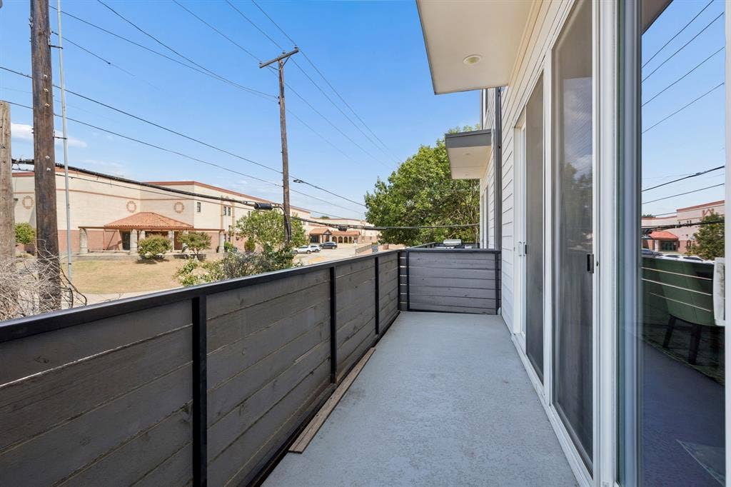 1901 N Carroll Avenue, #104, Dallas, TX 75204 Private balcony featuring horizontal wood-plank railing, concrete flooring, and sliding glass door entry