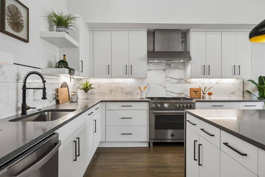 1901 N Carroll Avenue, #104, Dallas, TX 75204 Kitchen featuring white flat-panel cabinetry, stone-finish countertops, full-height stone-patterned backsplash, stainless steel professional-style range with matching vent hood, and wood-finish flooring