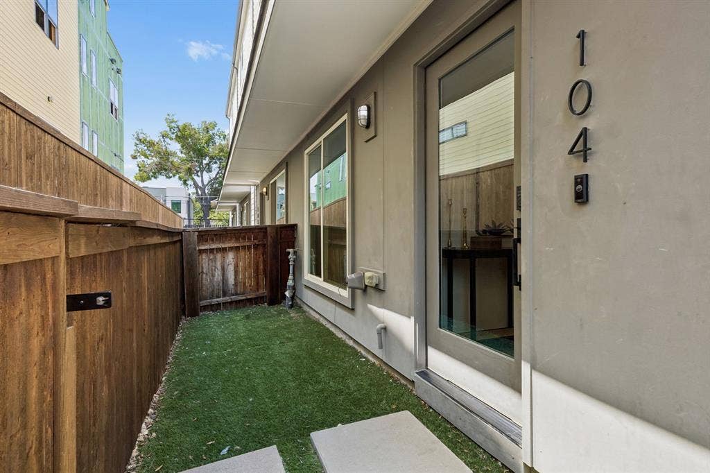 1901 N Carroll Avenue, #104, Dallas, TX 75204 Private patio featuring synthetic turf, wood-privacy fencing, and a glass-paneled entry door