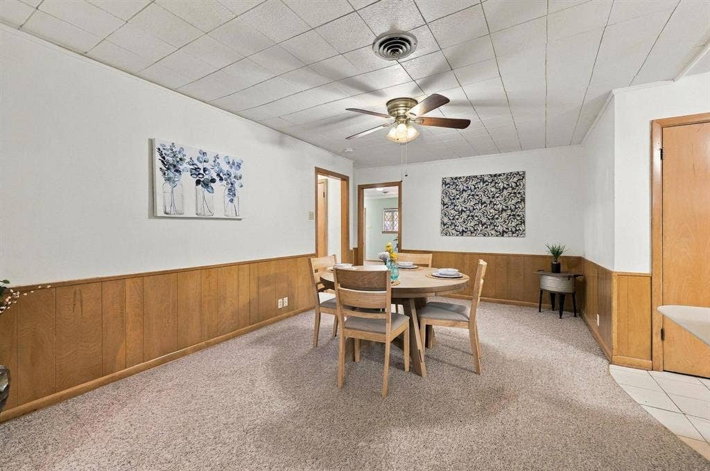 Dining area featuring wood-paneled wainscoting, with easy access to the kitchen