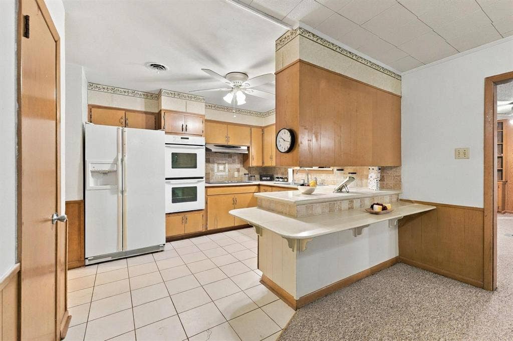 Built in cabinetry with double oven, stove top, plenty of cabinetry and a multi-level peninsula with a countertop extension