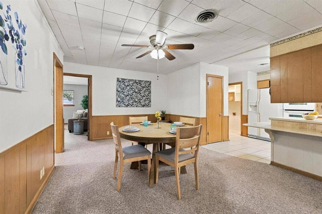 Dining area featuring wood-paneled wainscoting, with easy access to the kitchen