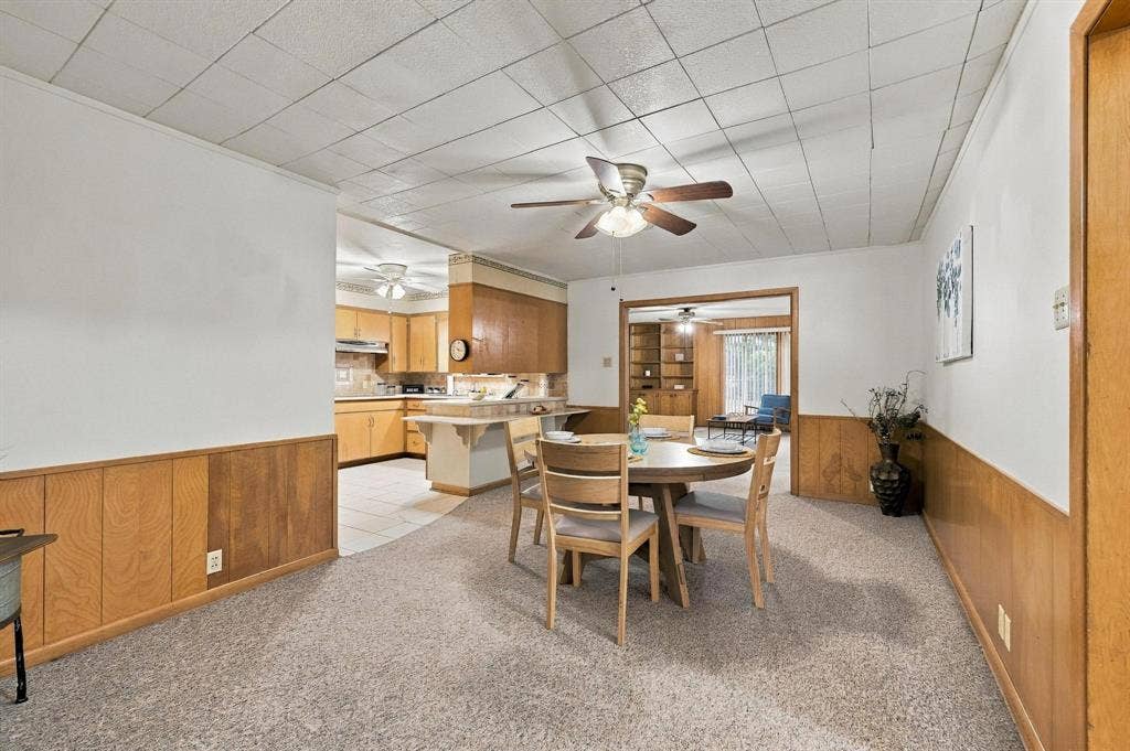 Dining area featuring wood-paneled wainscoting, with easy access to the kitchen