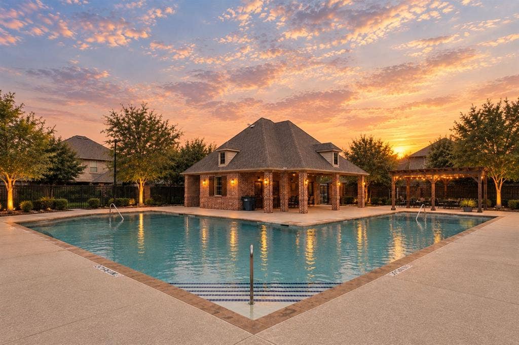 L-shaped sparkling swimming pool with concrete decking, brick-constructed pavilion, wood-frame pergola
