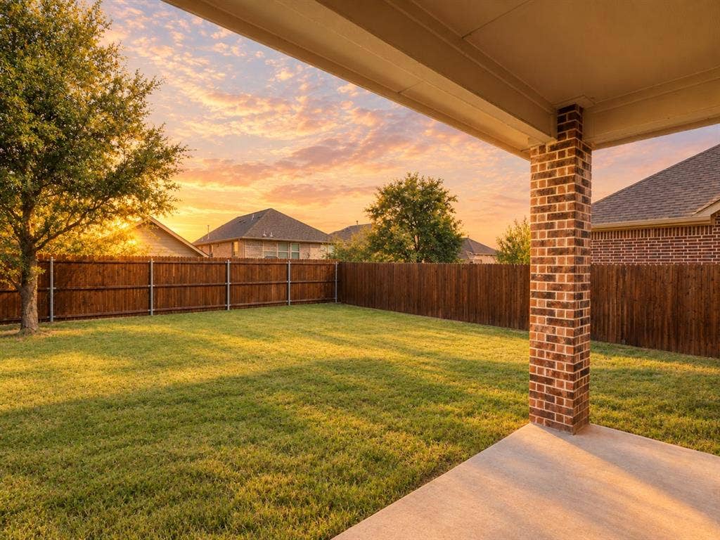 Covered concrete patio overlooking a fenced backyard with lawn space