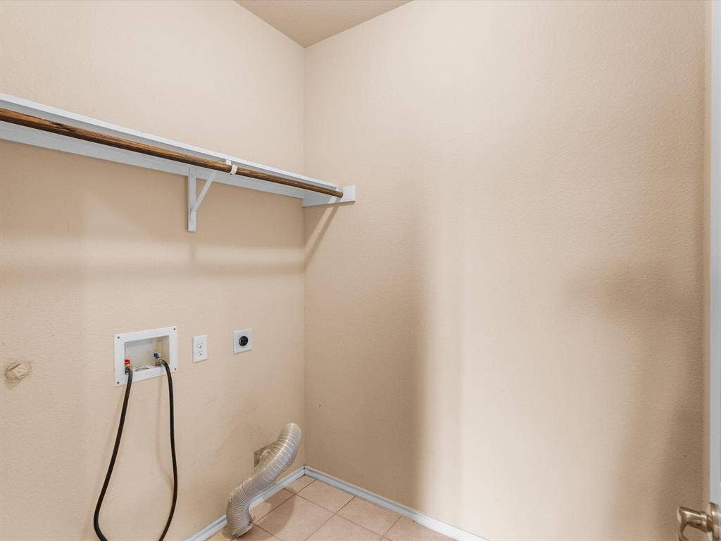 Utility room featuring tile flooring, neutral wall paint, and a built-in wall-mounted storage shelf with a hanging rod