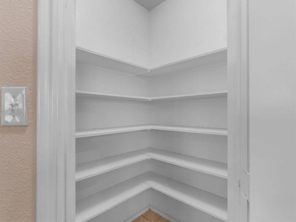 Built-in storage pantry featuring white corner shelving and a white door frame