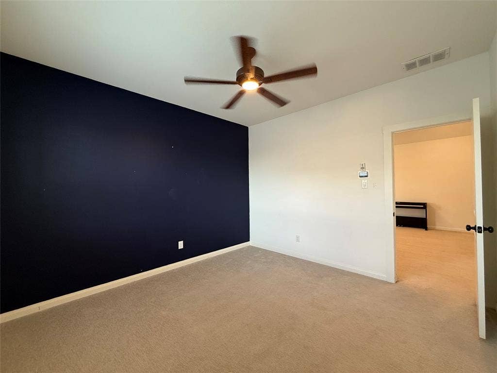 12905 Yale Court, Frisco, TX 75035 Room featuring a dark-toned accent wall, neutral carpeting, and a central ceiling fan with integrated lighting