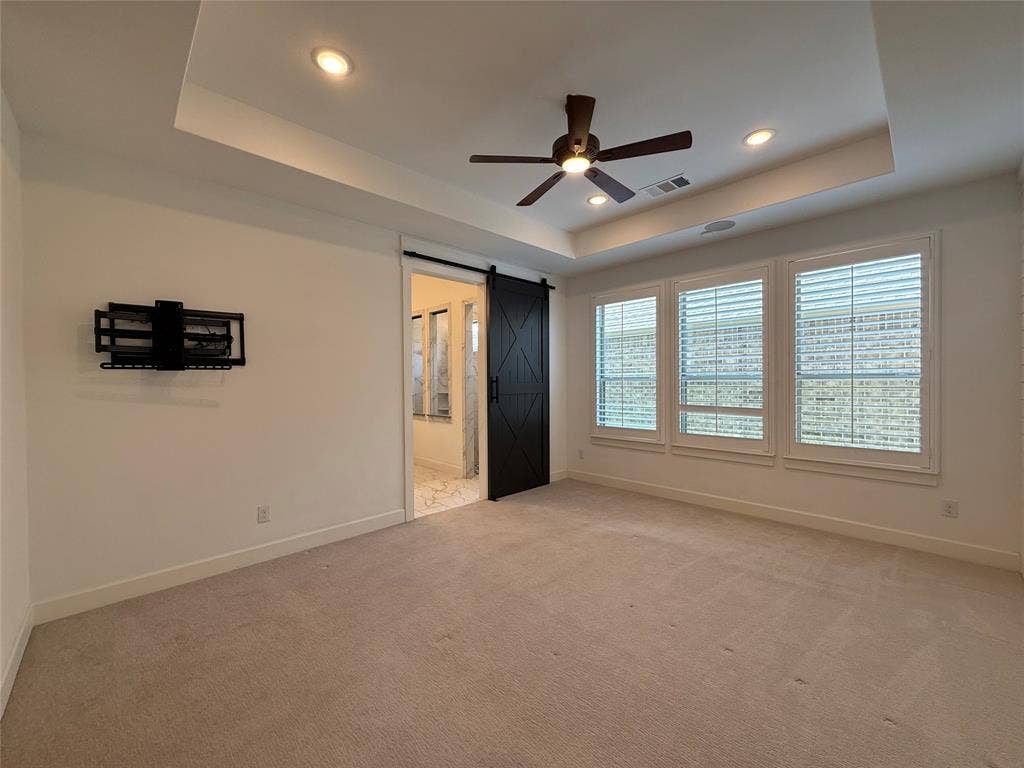 12905 Yale Court, Frisco, TX 75035 Tray ceiling with recessed lighting, black barn door, neutral carpeting, and plantation shutters