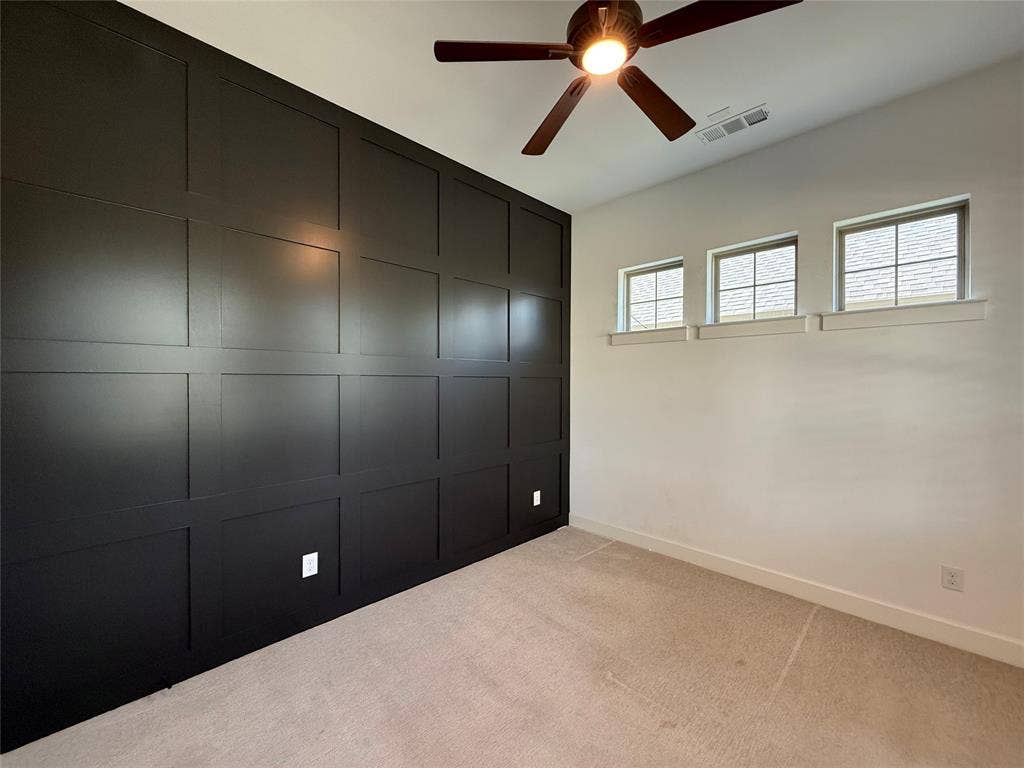 12905 Yale Court, Frisco, TX 75035 Accent wall featuring black grid molding, neutral carpeting, three high-set windows with grid muntins, and an attached ceiling fan with integrated lighting