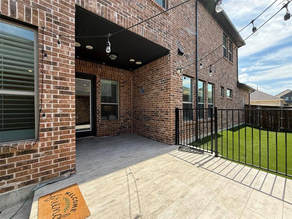 12905 Yale Court, Frisco, TX 75035 Covered brick patio featuring stone-tile flooring, recessed lighting, and a black metal perimeter fence enclosing an artificial turf lawn