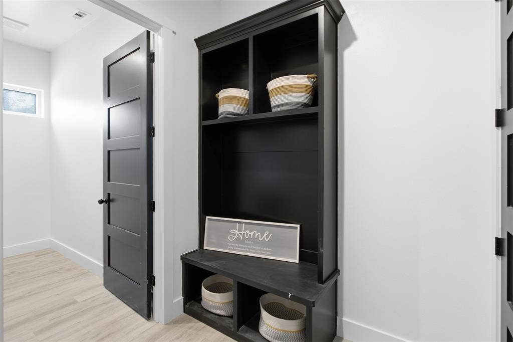 Built-in black hall tree with integrated bench seating, wood-finish flooring, and solid-core four-panel interior doors
