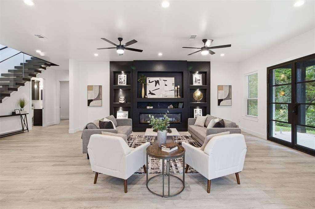 Living area featuring wood-finish flooring, a matte black built-in fireplace with integrated shelving, recessed lighting, double ceiling fans, and black-framed glass paneled doors