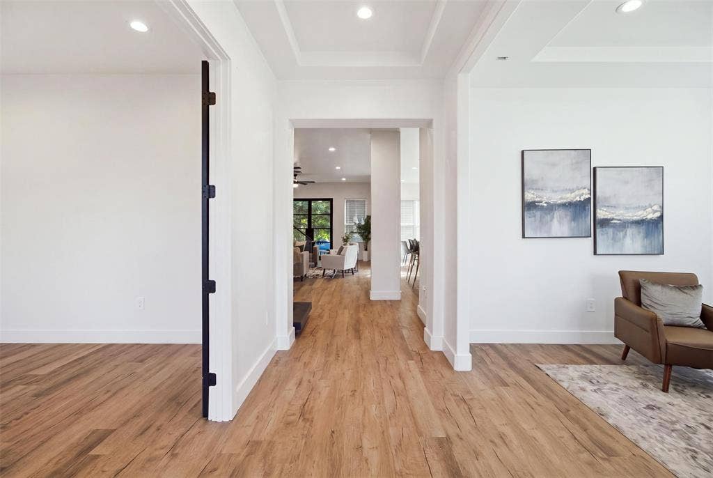 Interior space featuring wood-finish flooring, recessed lighting, tray ceilings, and heavy-duty matte black door hinges
