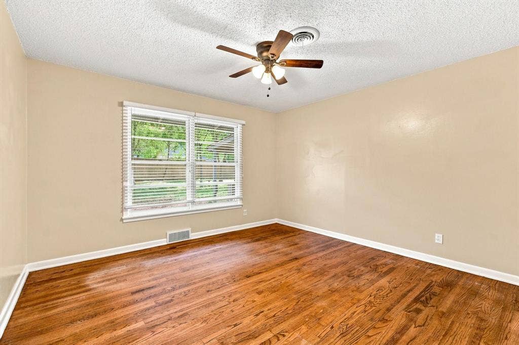 Room featuring wood-finish flooring, a ceiling fan with integrated lighting, and a window with horizontal blinds
