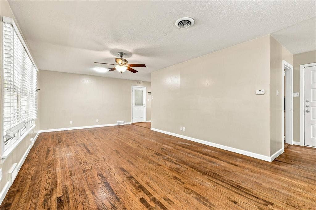 Living area featuring wood-finish flooring, a ceiling fan with integrated lighting, horizontal window blinds, and paneled doors