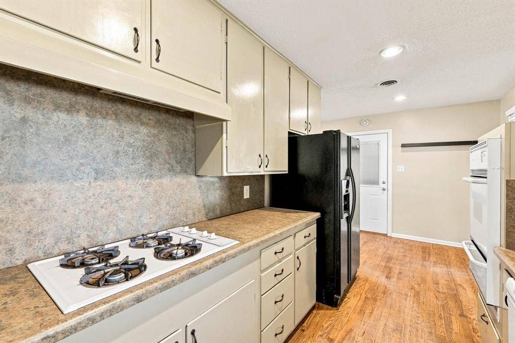 Kitchen featuring solid-surface countertops, integrated cooktop, wood-finish flooring, recessed ceiling lighting, and built-in wall oven