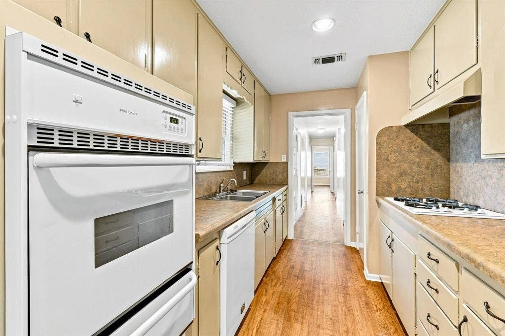 Kitchen featuring built-in double wall ovens, integrated cooktop, laminate countertops, wood-finish flooring, and recessed ceiling lighting