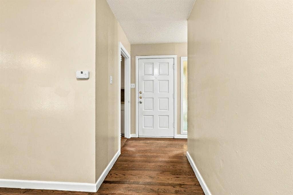 Entryway featuring wood-finish flooring, a white paneled door with hardware, and a side-light window panel