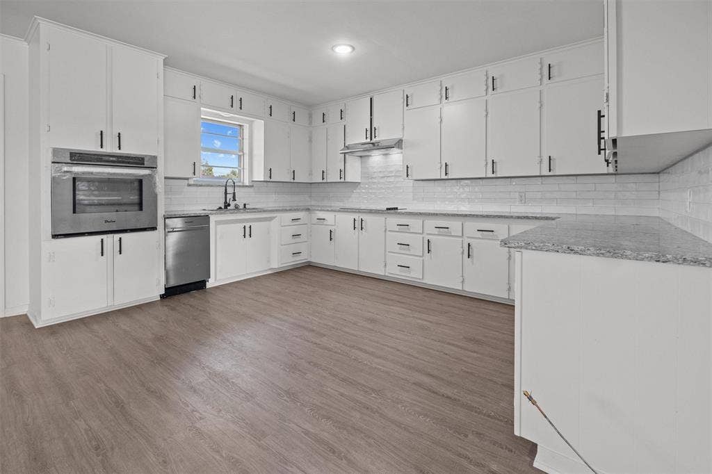 17014 Woodcrest Circle, Lindale, TX 75771 Kitchen featuring white cabinetry, stone-finish countertops, subway tile backsplash, stainless steel built-in oven, and wood-finish flooring
