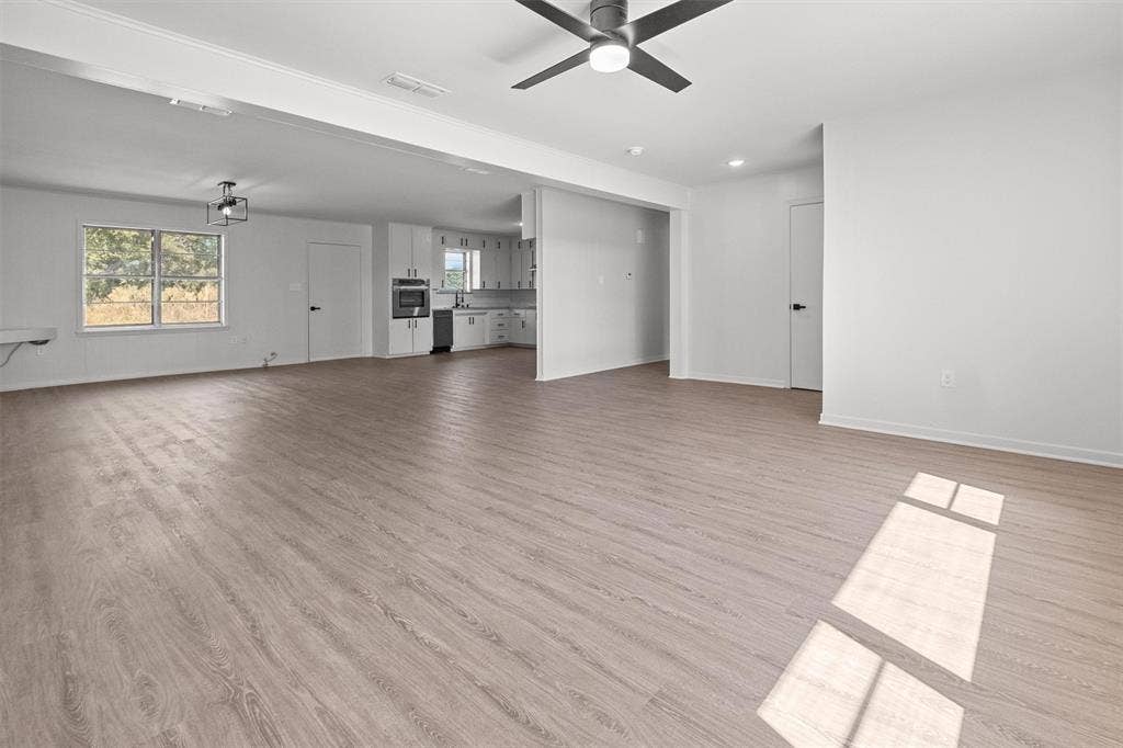 17014 Woodcrest Circle, Lindale, TX 75771 Open-concept interior featuring light wood-finish flooring, a contemporary ceiling fan, recessed lighting, and kitchen cabinetry with integrated appliances