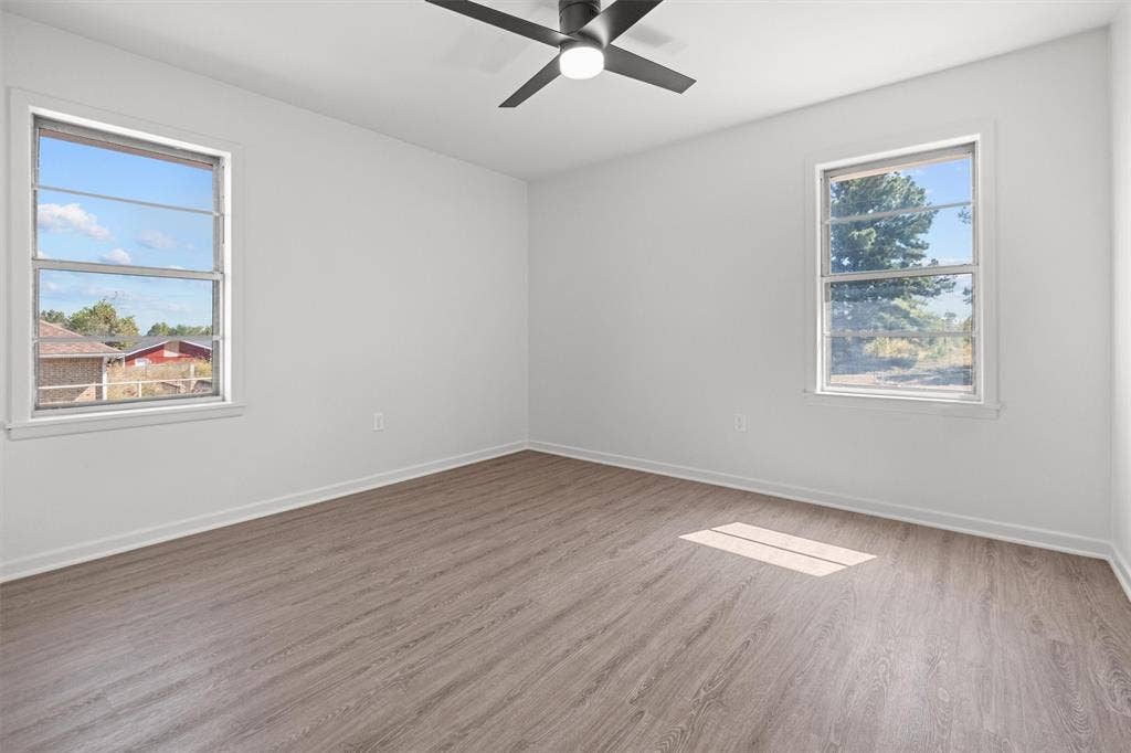 17014 Woodcrest Circle, Lindale, TX 75771 Interior space featuring wood-finish flooring, white walls, dual windows, and a matte black ceiling fan with integrated lighting