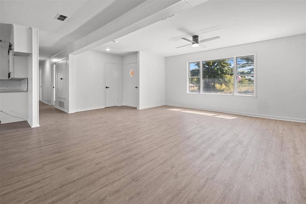 17014 Woodcrest Circle, Lindale, TX 75771 Open-concept interior featuring wood-finish flooring, a ceiling fan with integrated lighting, and a large multi-pane window