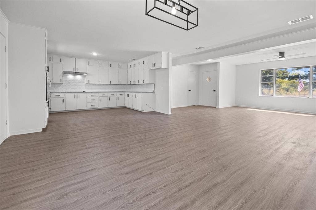 17014 Woodcrest Circle, Lindale, TX 75771 White cabinetry, white subway tile backsplash, wood-finish flooring, and geometric black metal pendant lighting