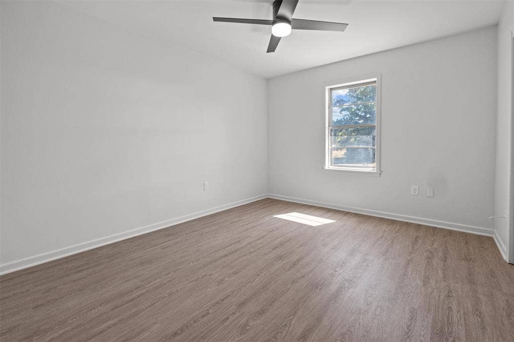 17014 Woodcrest Circle, Lindale, TX 75771 Room featuring wood-finish flooring, a matte black ceiling fan with integrated lighting, and a single-pane window