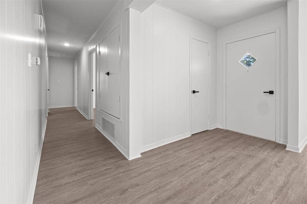 17014 Woodcrest Circle, Lindale, TX 75771 Neutral-toned wood-finish flooring, white paneled walls, matte black hardware, and an exterior door with a diamond-shaped accent window