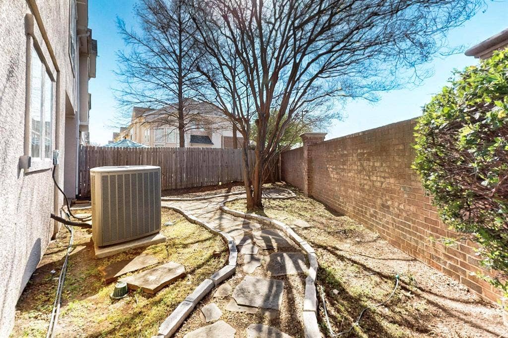 2606 Rue De Ville, Irving, TX 75038 Side yard featuring a stone pathway, mature tree, brick perimeter wall, and wood-panel fencing