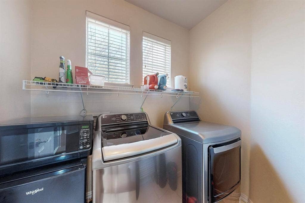 2606 Rue De Ville, Irving, TX 75038 Laundry area featuring two windows with horizontal blinds and an installed wire shelving unit