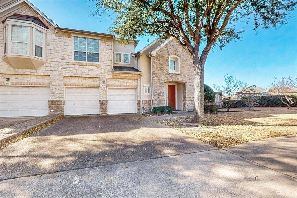 2606 Rue De Ville, Irving, TX 75038 Multi-unit exterior featuring a textured stone facade, bay window, two attached garage bays, and a concrete driveway