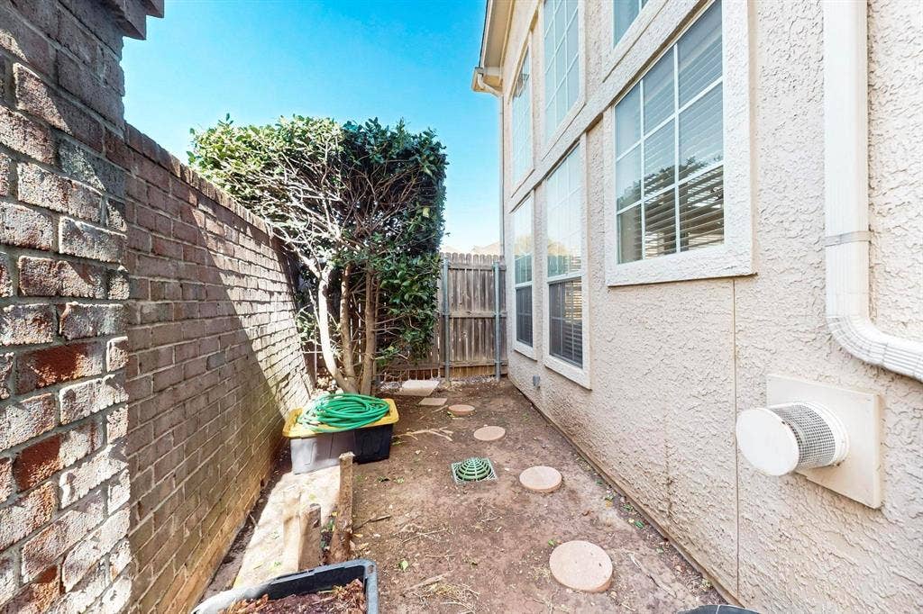 2606 Rue De Ville, Irving, TX 75038 Exterior side yard featuring a brick retaining wall, stucco siding, and multi-pane windows