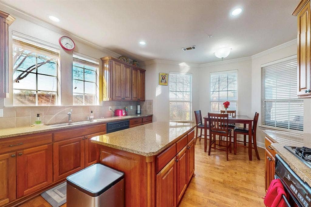 2606 Rue De Ville, Irving, TX 75038 Kitchen featuring stained wood cabinetry, stone countertops, central island, wood-finish flooring, and multiple large windows