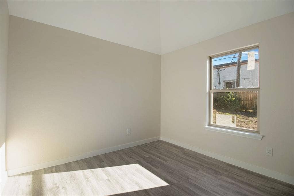 Neutral-toned walls, wood-finish flooring, and a single window with white trim